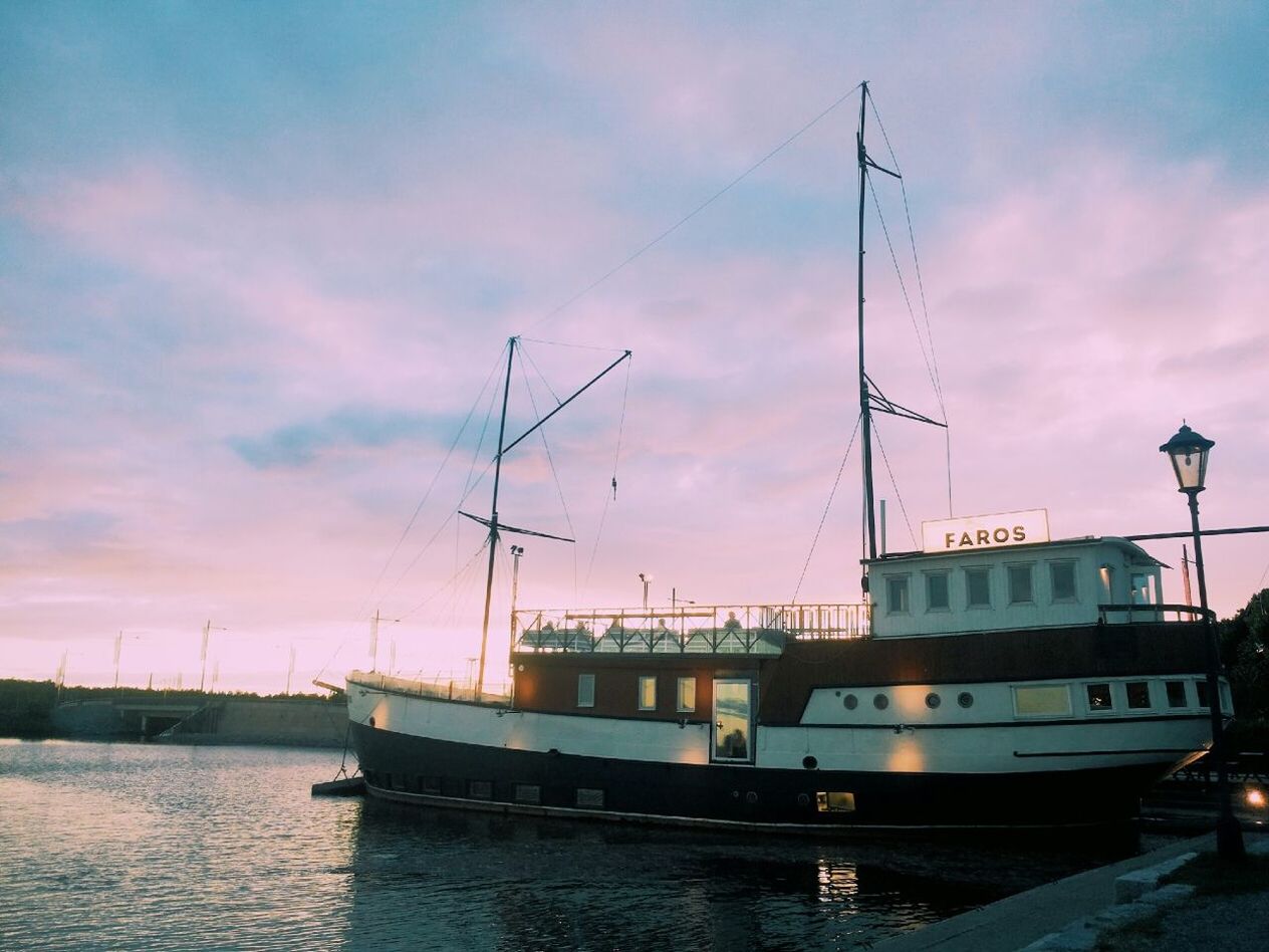 BOATS MOORED IN SEA AT SUNSET