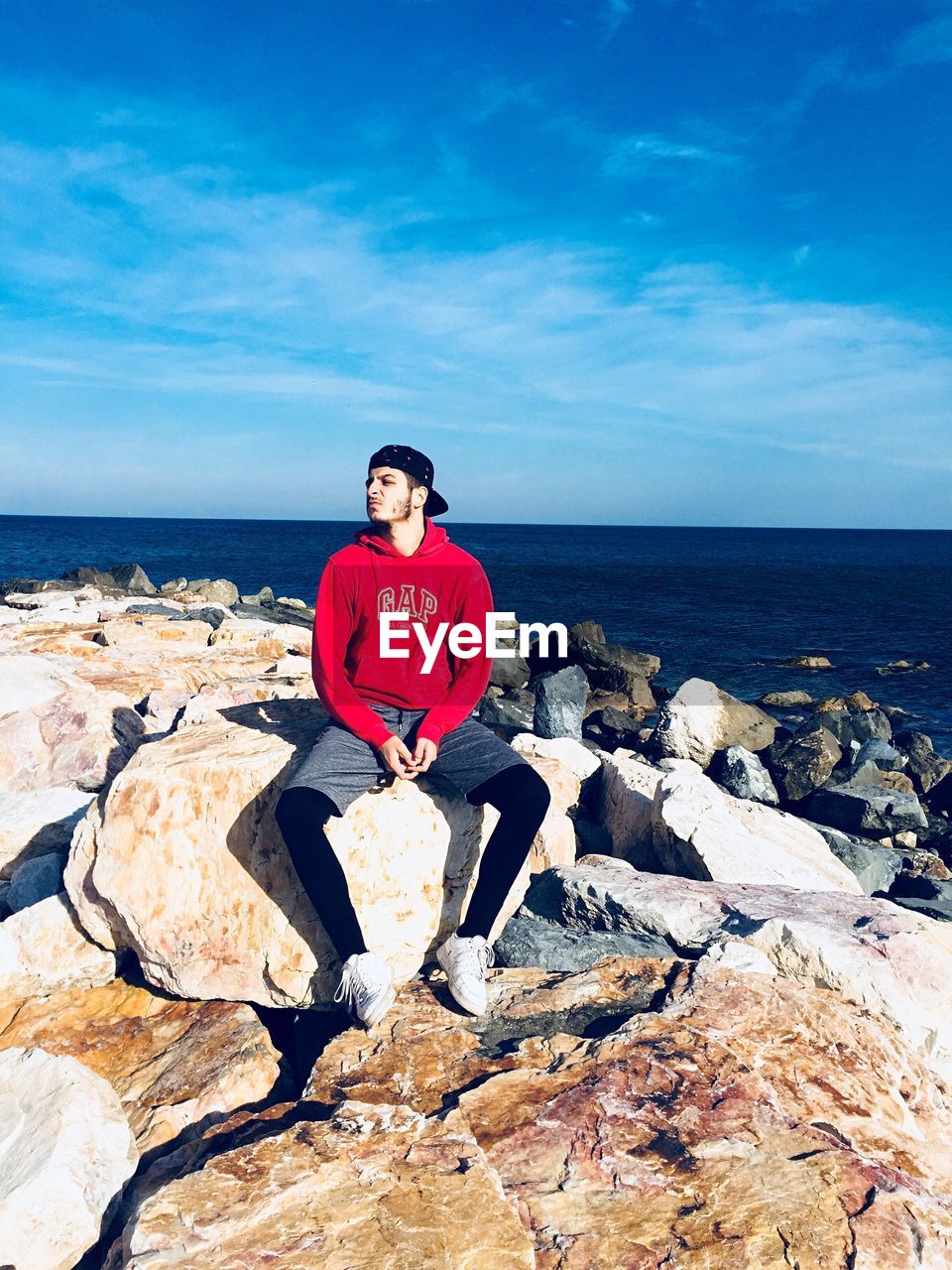 PORTRAIT OF MAN ON ROCK AGAINST SKY