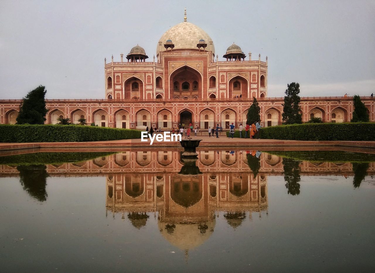 REFLECTION OF BUILDING IN LAKE WITH WATER IN FOREGROUND