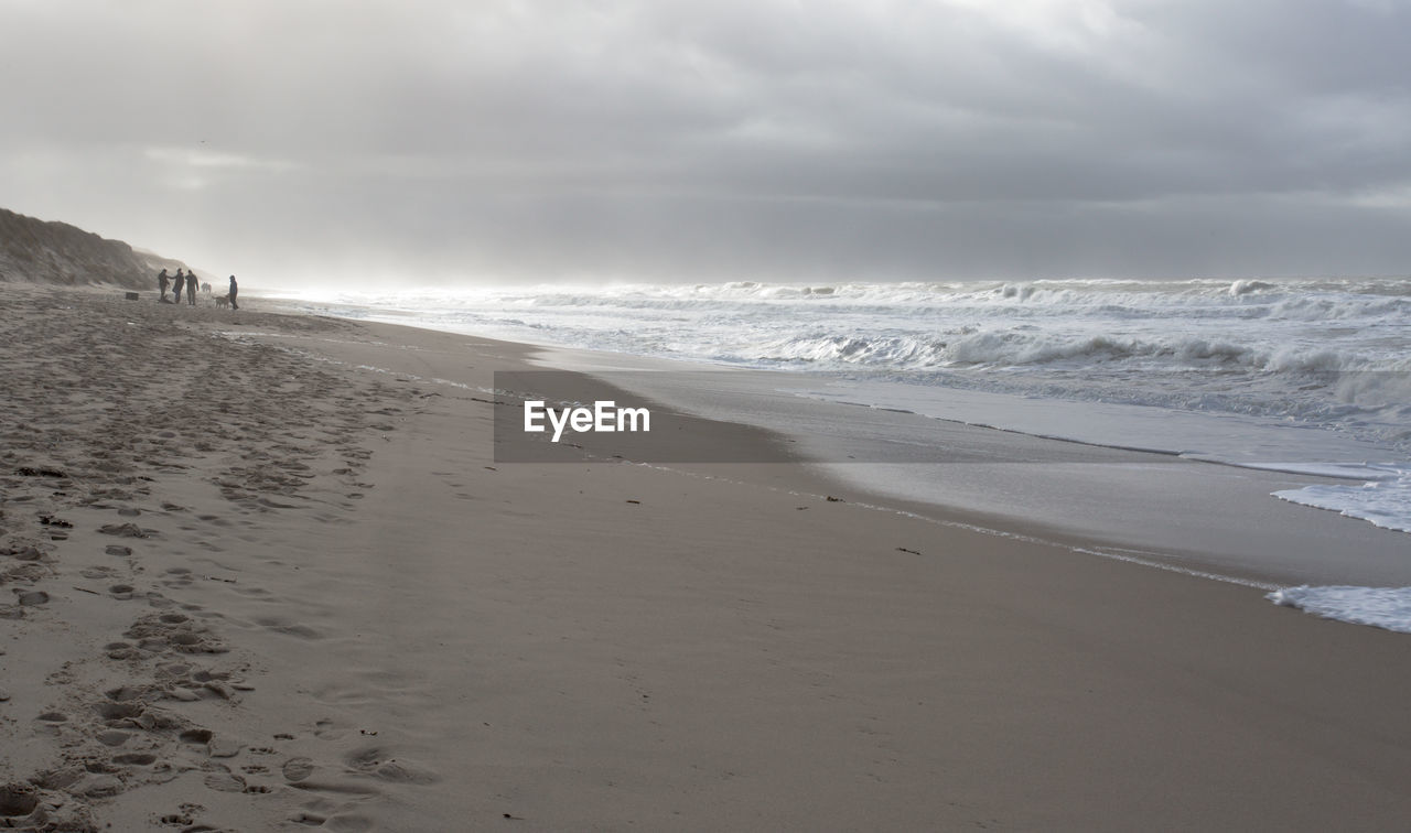 Scenic view of beach against cloudy sky