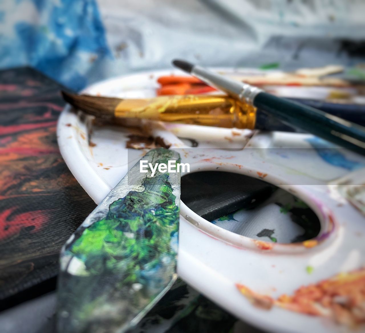 Close-up of messy paintbrushes and palette on table