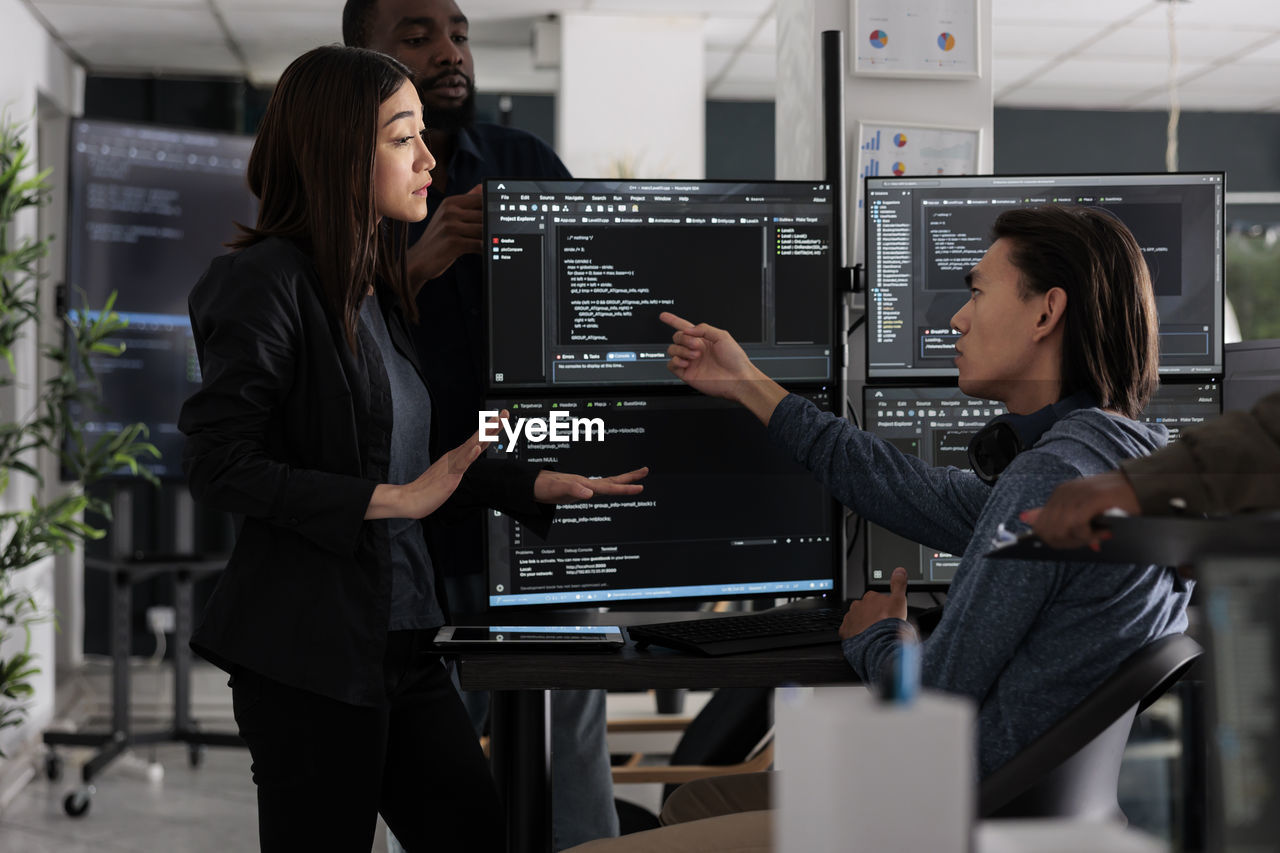 rear view of woman using mobile phone while standing in office