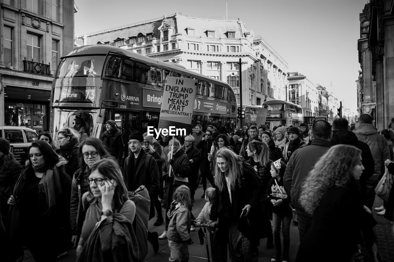 GROUP OF PEOPLE STANDING ON STREET AGAINST BUILDINGS IN CITY