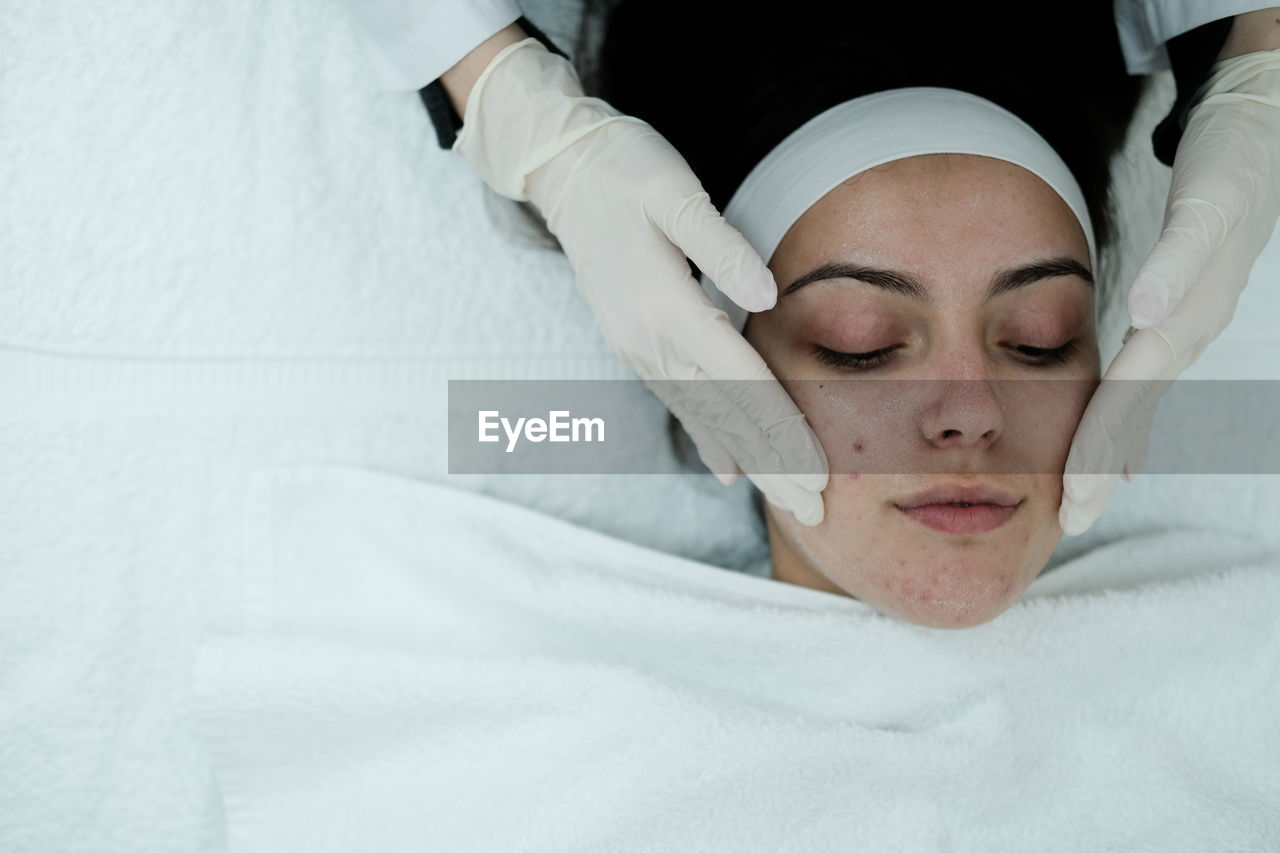 Cosmetologist cleaning woman's face before applying face treatments