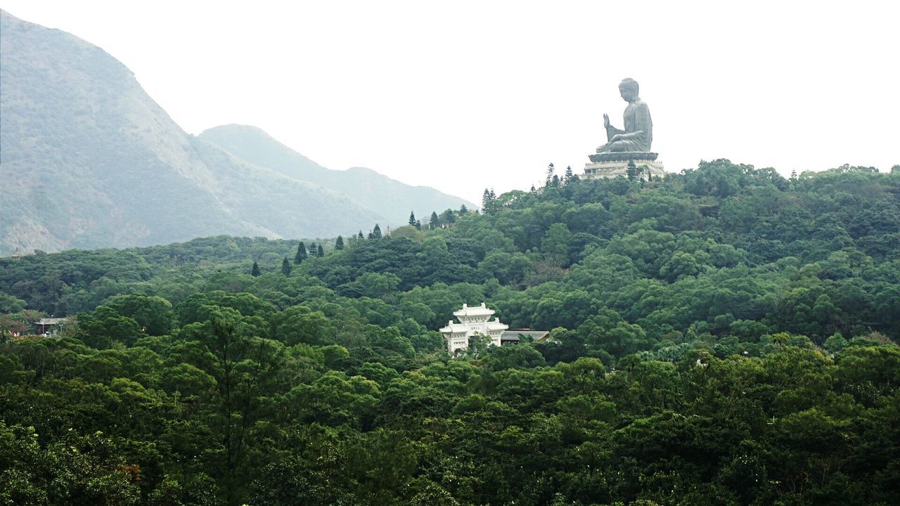 Tian tan buddha by mountain against clear sky