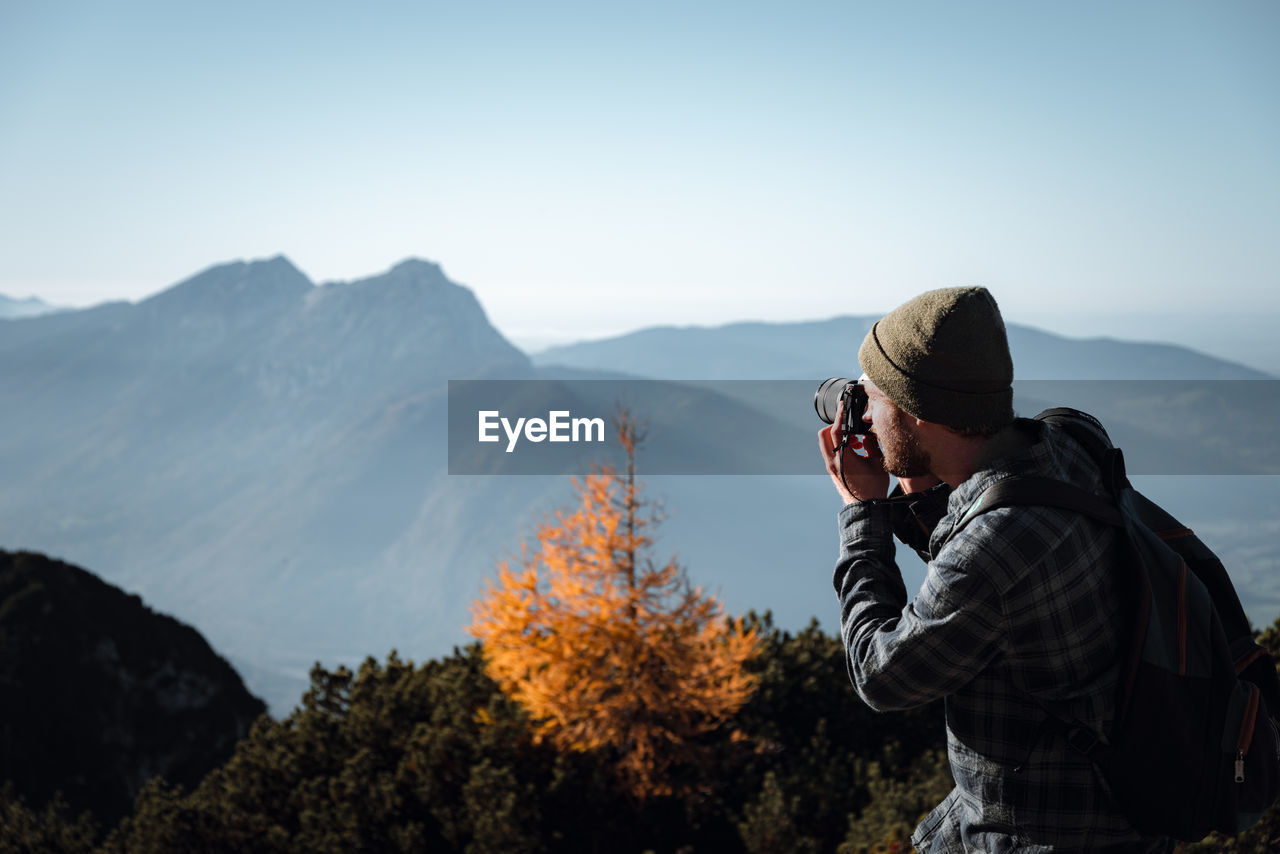 Man photographing on mountain against sky