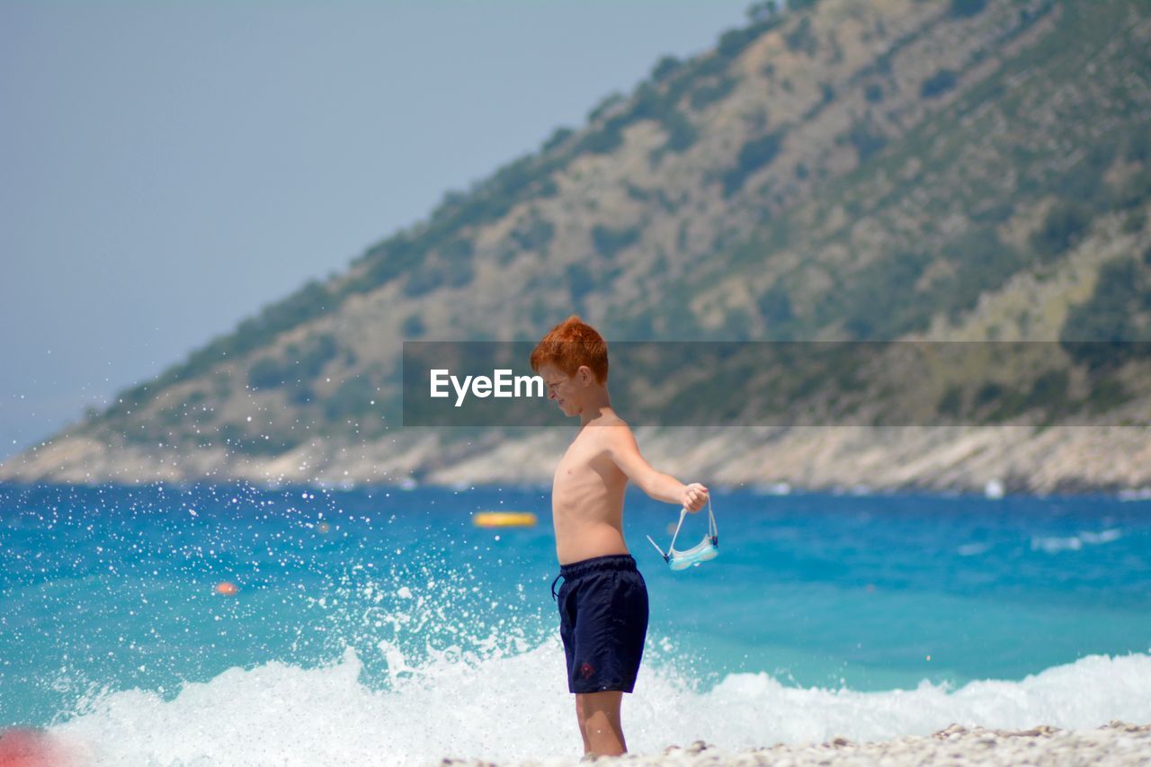 Shirtless boy standing on beach