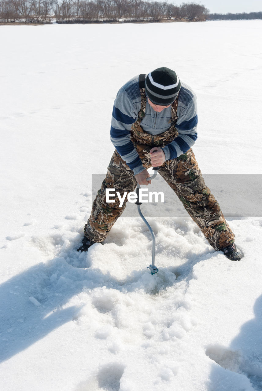 Mid adult man subglacial fishing in frozen lake