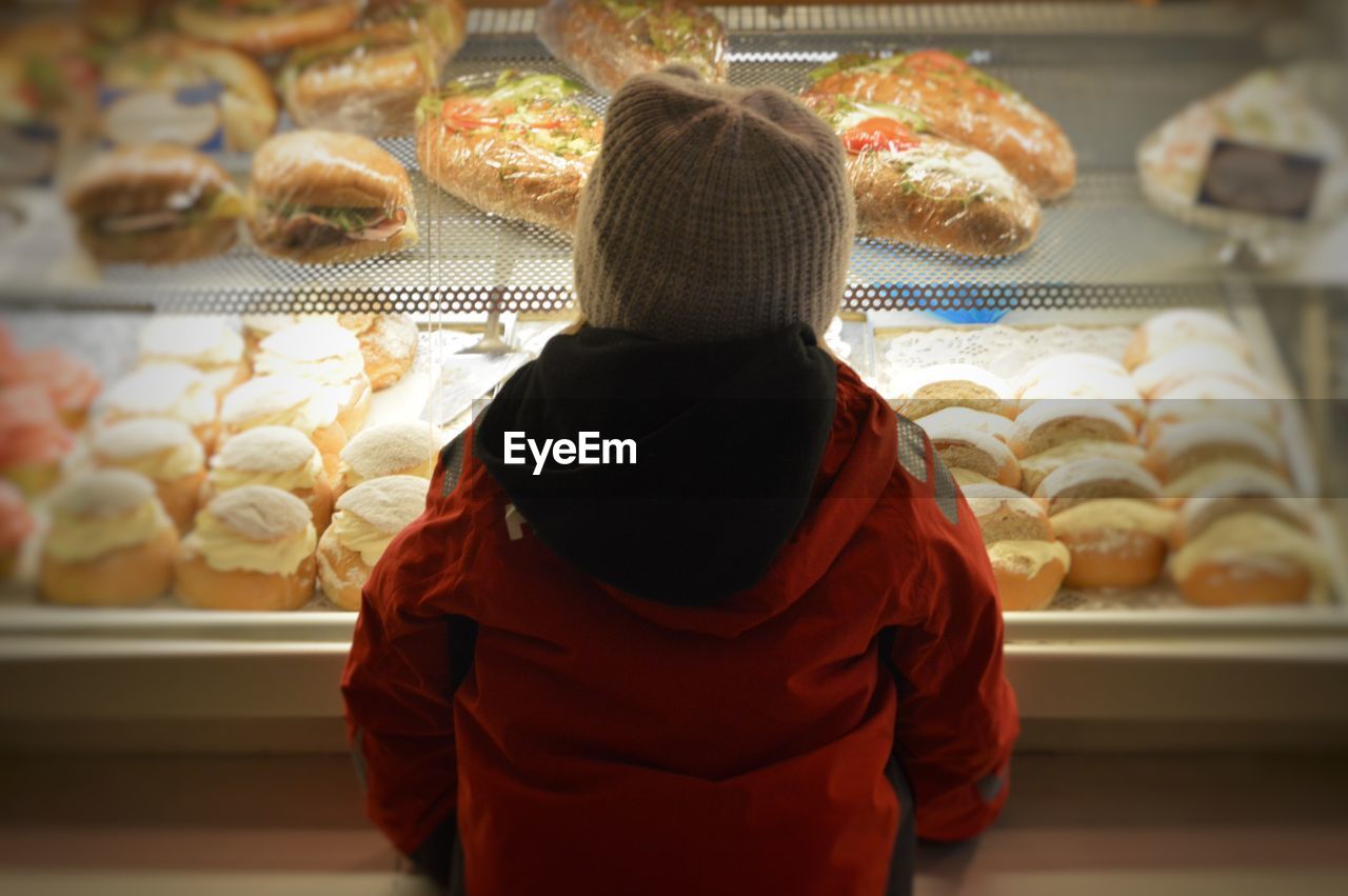 Rear view of girl looking towards food in display cabinet