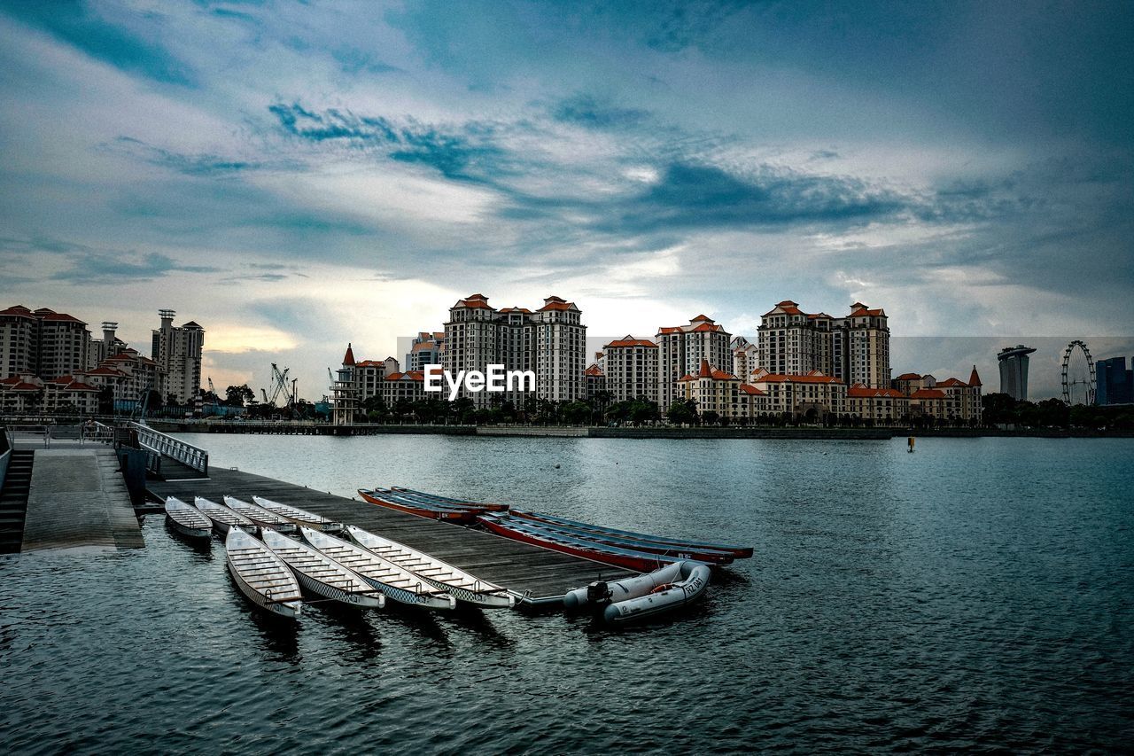 BUILDINGS BY RIVER AGAINST SKY IN CITY