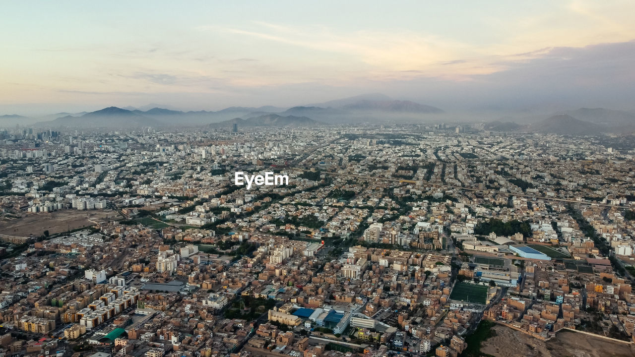 HIGH ANGLE VIEW OF TOWNSCAPE AGAINST SKY DURING SUNSET