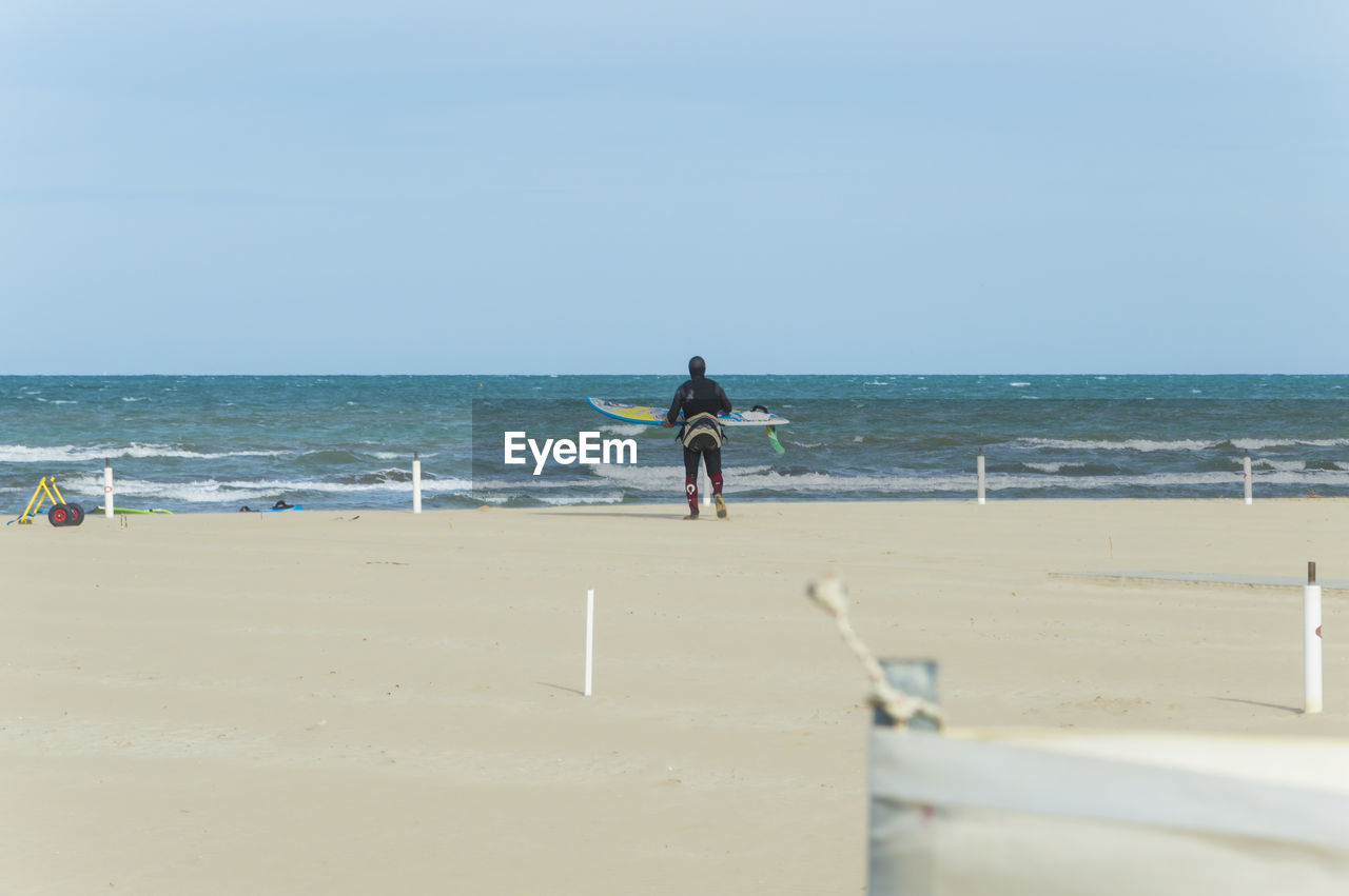 Rear view of man with surfboard walking at beach