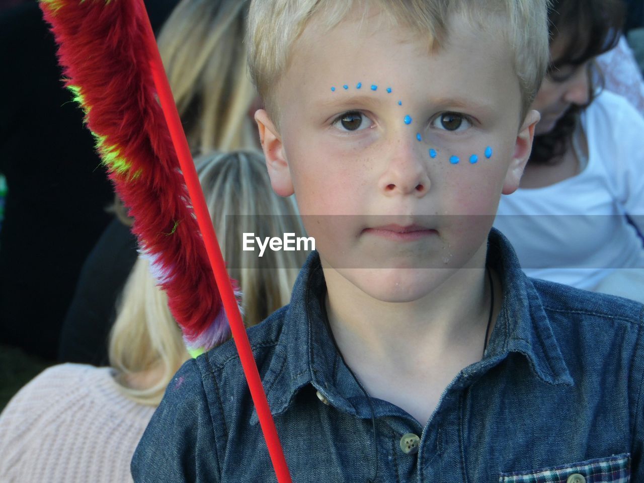 Close-up portrait of cute boy with blue paint spots on face