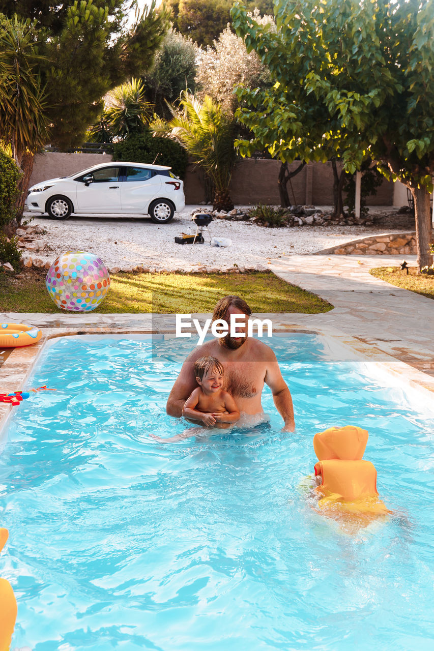 Dad swimming with his son in the pool in the yard