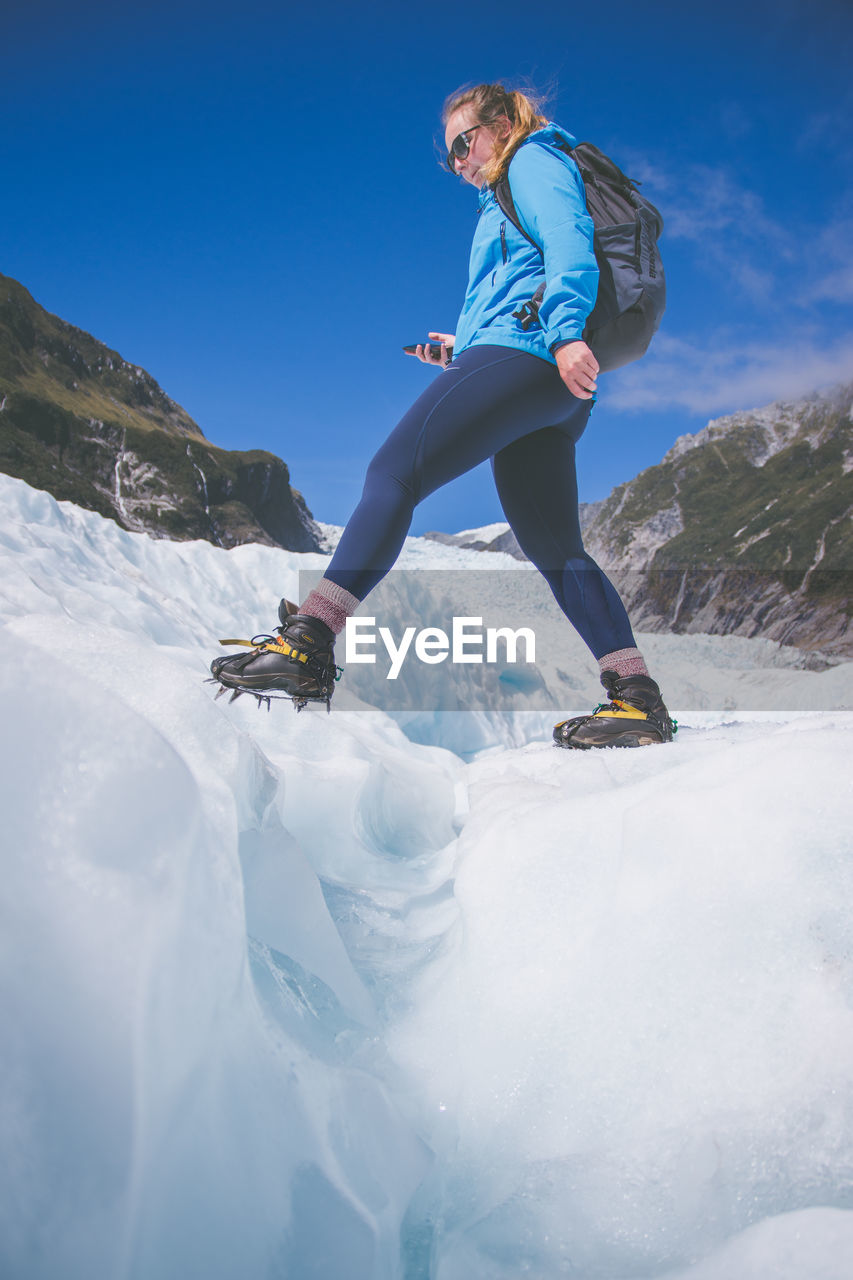 Low angle view of woman standing on snowcapped mountain