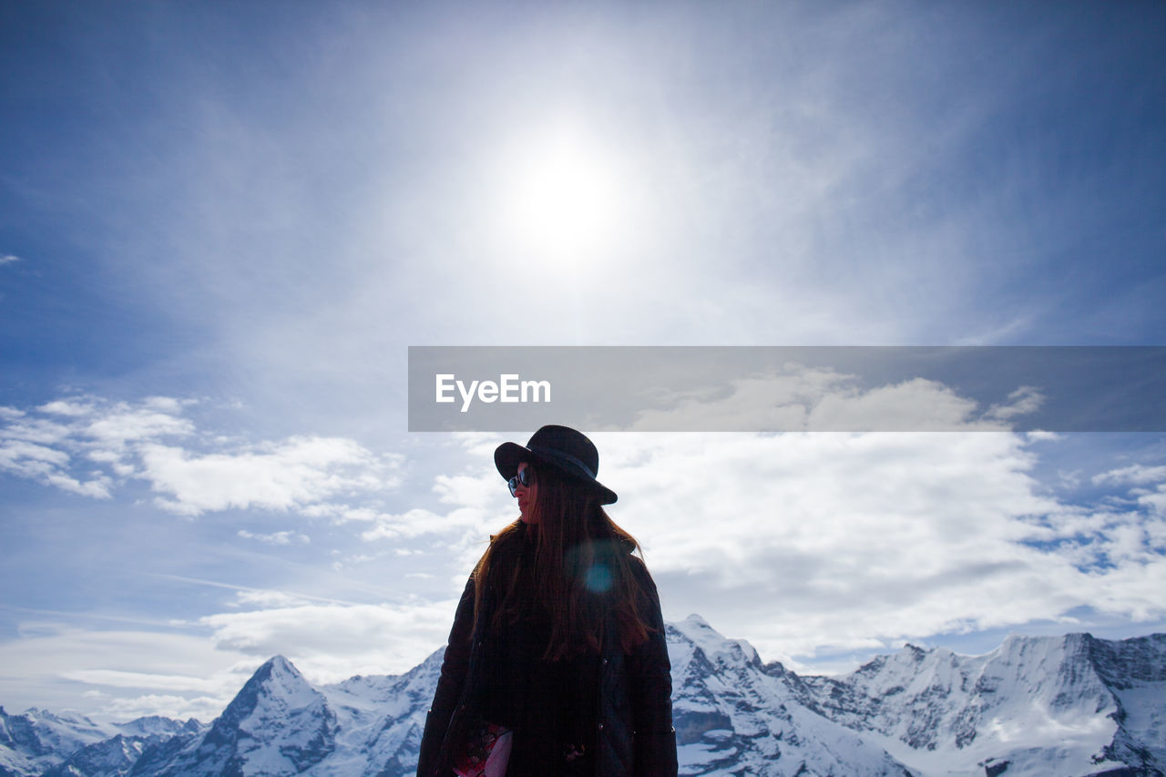 Woman standing against snow covered mountains and sky