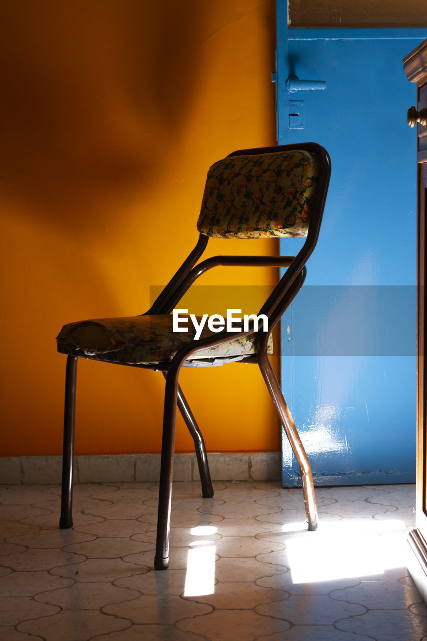 Empty chair and table against wall at home