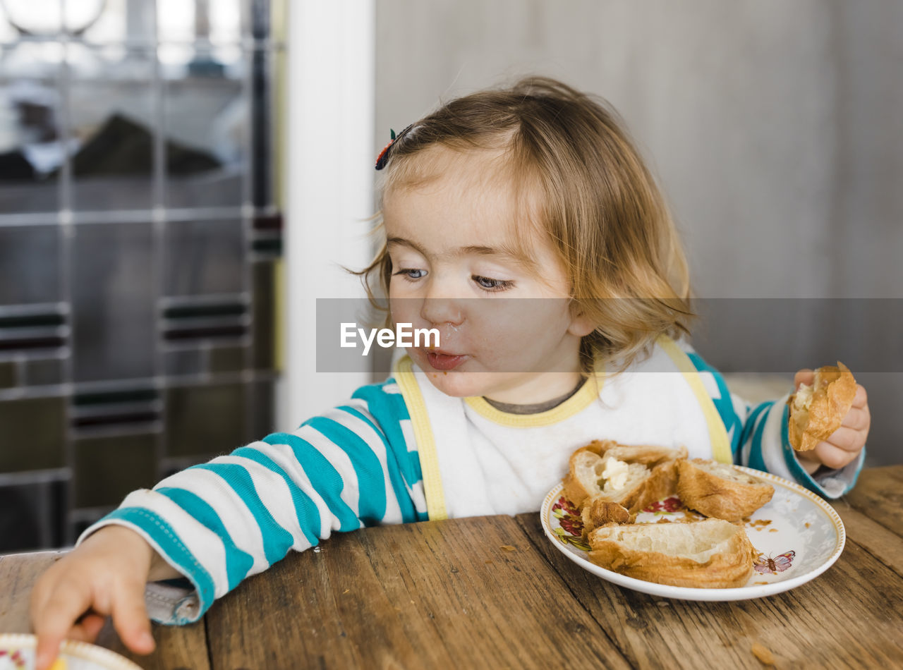 Close-up of cute girl eating food on table at home