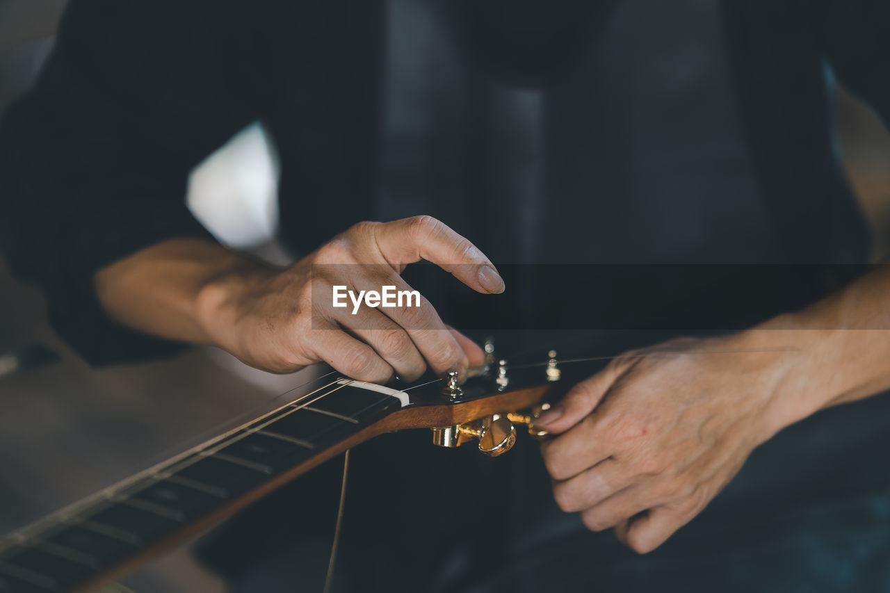 cropped hand of man playing guitar