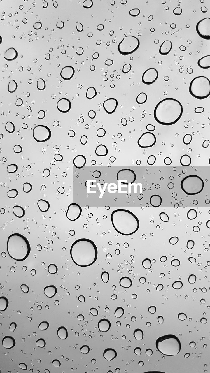 CLOSE-UP OF RAINDROPS ON GLASS WINDOW