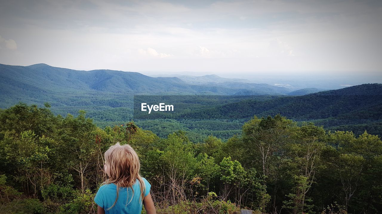 Rear view of girl on landscape against sky