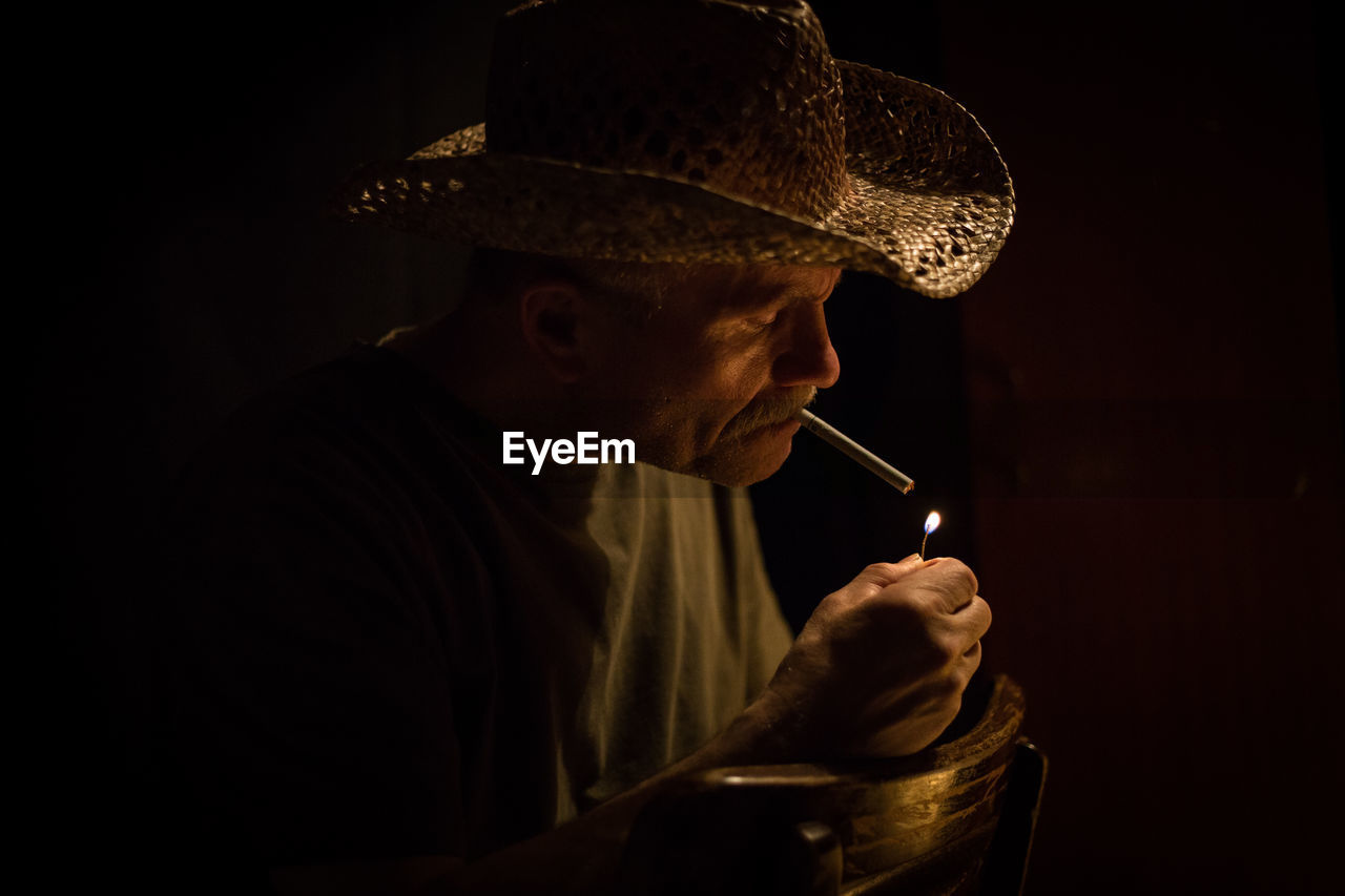 Senior man smoking cigarette in darkroom