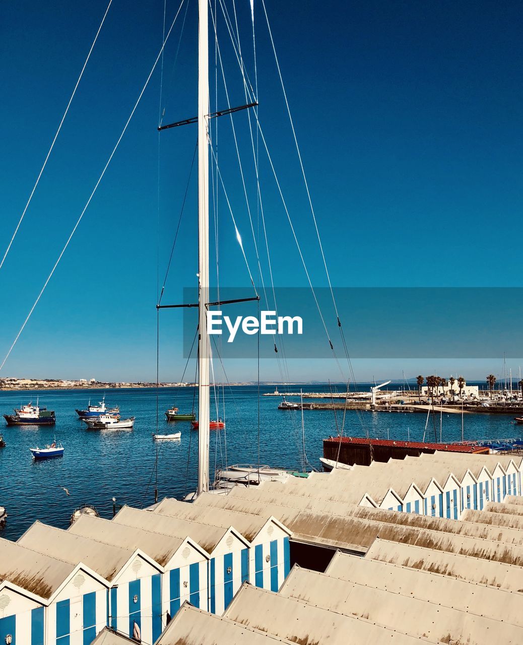 Sailboats moored in sea against blue sky
