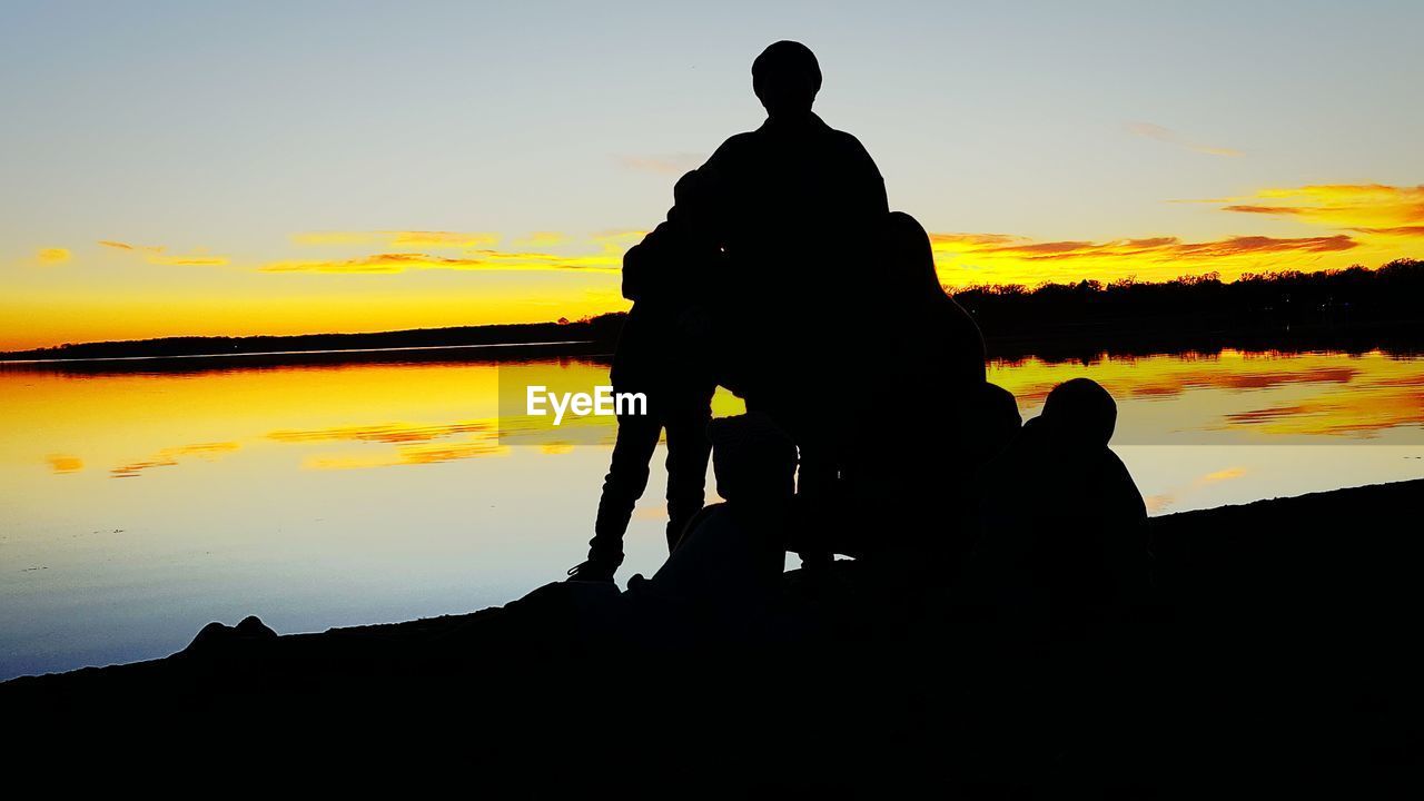 SILHOUETTE OF MAN WITH ARMS OUTSTRETCHED AGAINST SKY