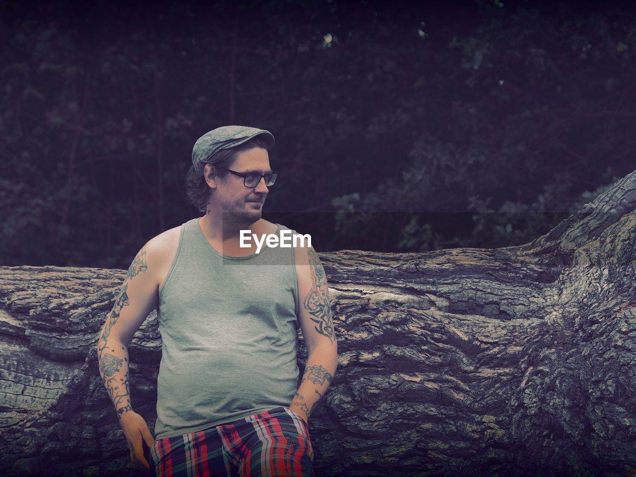 Hipster standing against log in forest