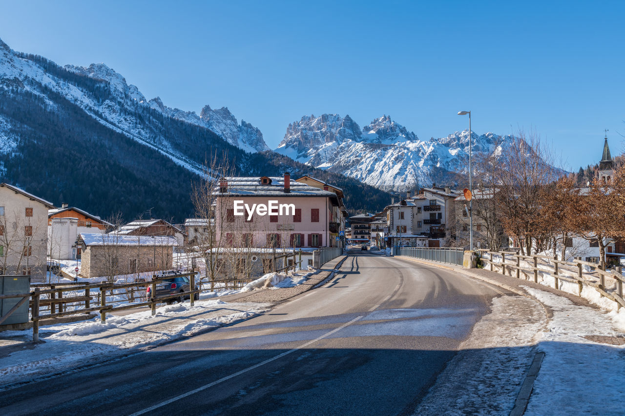 ROAD BY BUILDINGS AGAINST SKY DURING WINTER