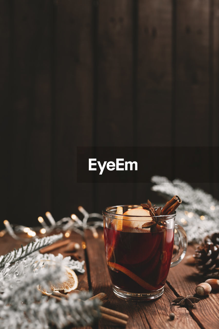 Christmas time concept photo. glass cup or mug with mulled wine inside on wooden table background