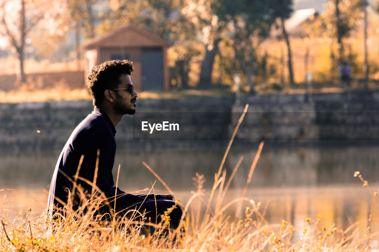 Side view of young man sitting on field