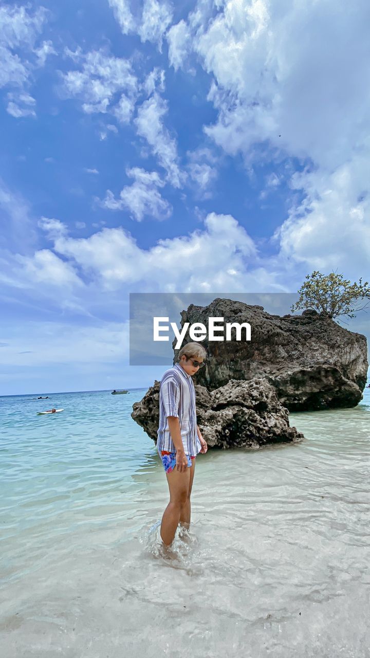 water, sea, vacation, ocean, shore, sky, coast, one person, beach, cloud, land, full length, nature, holiday, trip, leisure activity, beauty in nature, adult, day, body of water, sand, wave, women, rock, standing, blue, bay, casual clothing, lifestyles, young adult, travel, scenics - nature, outdoors, clothing, person, summer, travel destinations, tranquility, child, childhood, horizon over water, idyllic, female, fashion