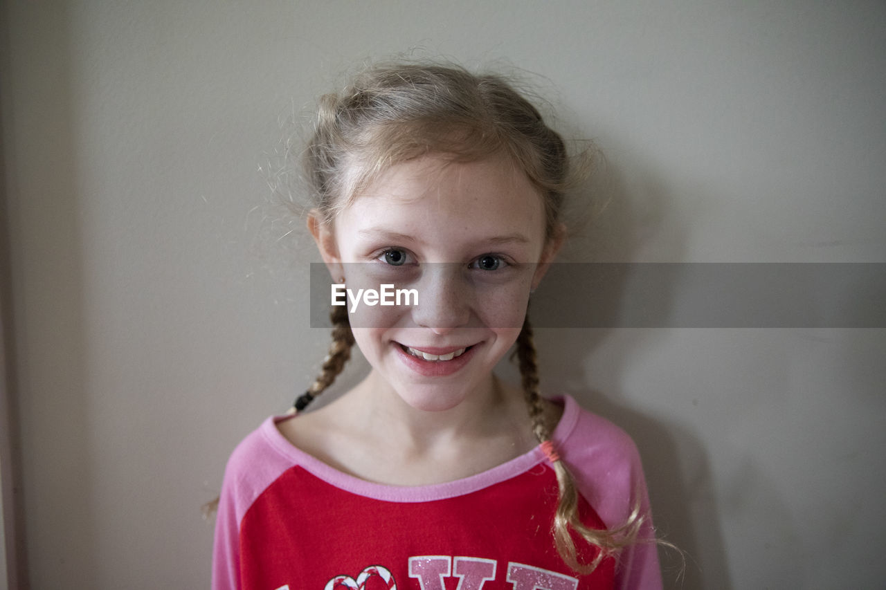 Blonde girl with french braids wearing pajamas smiles to camera