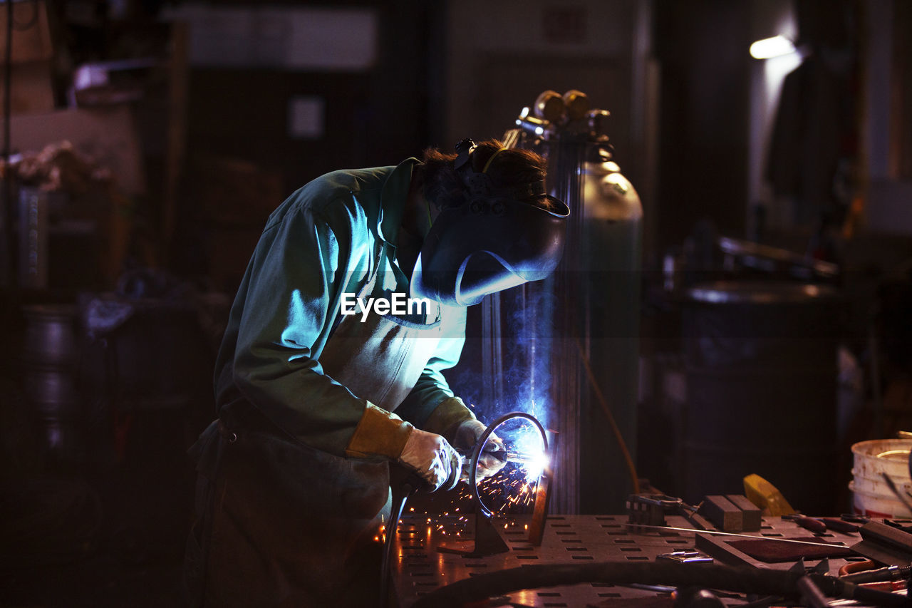 Side view of manual worker welding in workshop