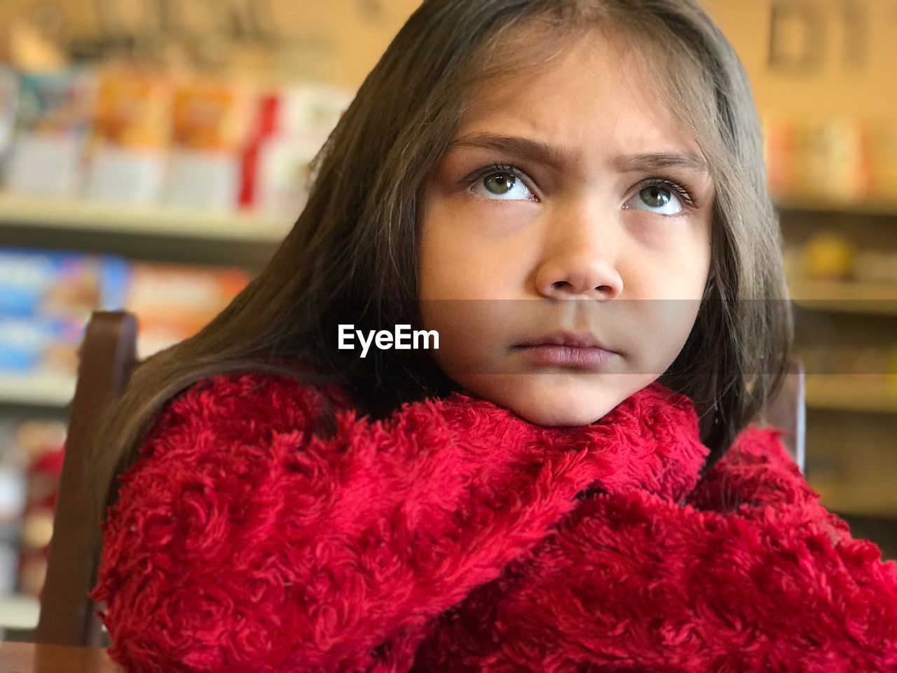 Close-up of girl wearing red warm clothing on chair