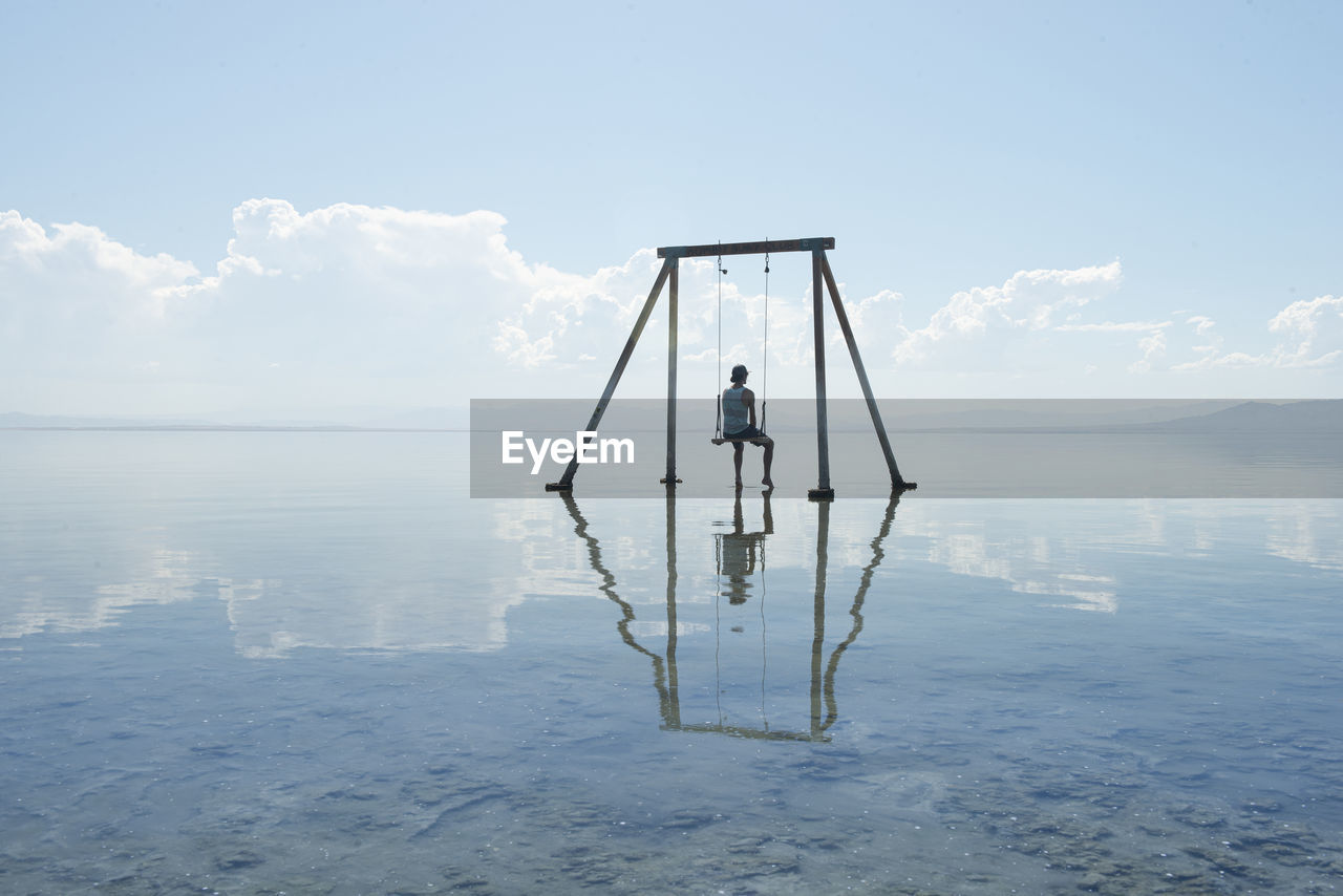 Self portrait on swing set in reflection on salton sea californi