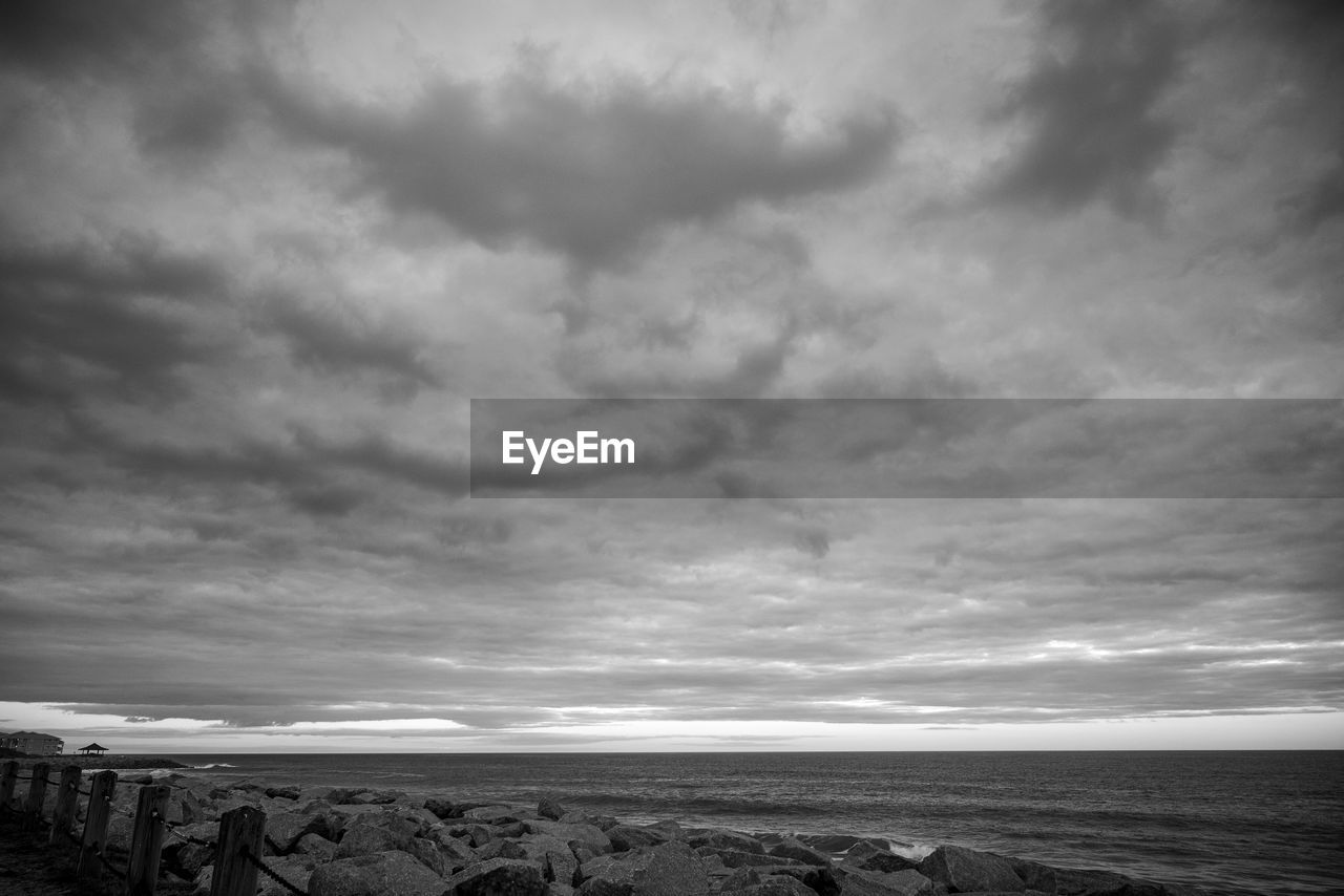 sky, cloud, sea, water, black and white, horizon, scenics - nature, land, beach, beauty in nature, nature, horizon over water, monochrome photography, monochrome, environment, tranquility, tranquil scene, darkness, ocean, dramatic sky, storm, landscape, no people, coast, wave, cloudscape, outdoors, overcast, seascape, non-urban scene, travel destinations, coastline, storm cloud, black, day, idyllic