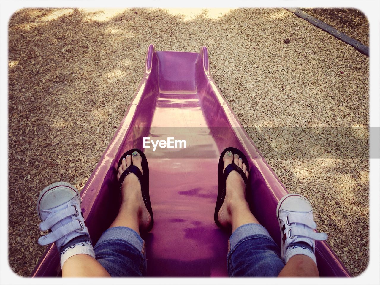 Low section of mother with child on slide at amusement park
