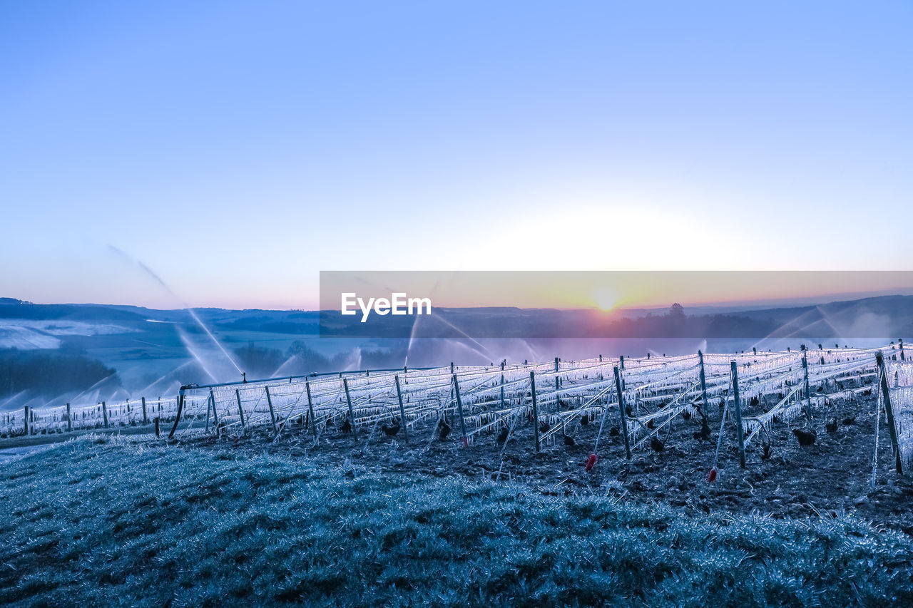 Scenic view of snowy field against sky during sunset