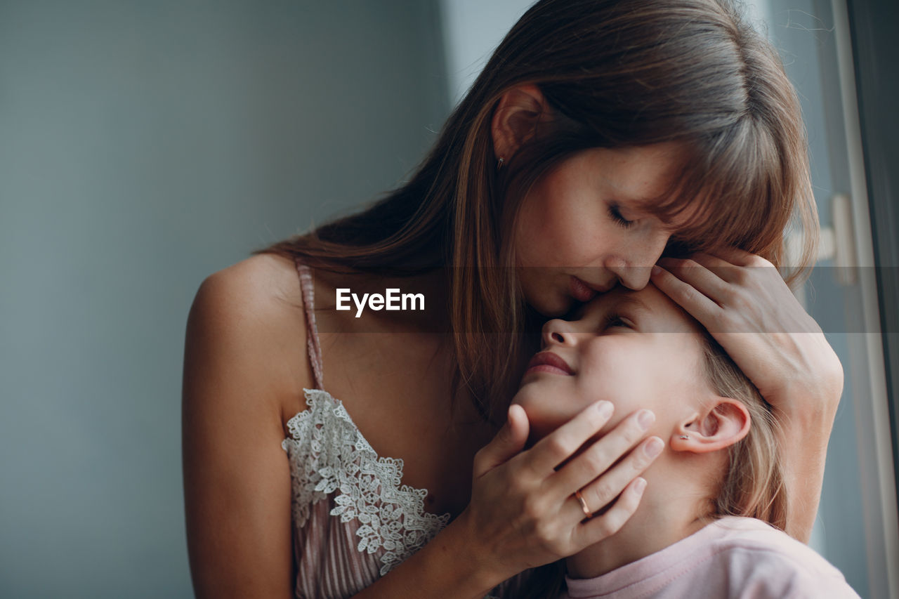 Close-up of mother kissing daughter at home