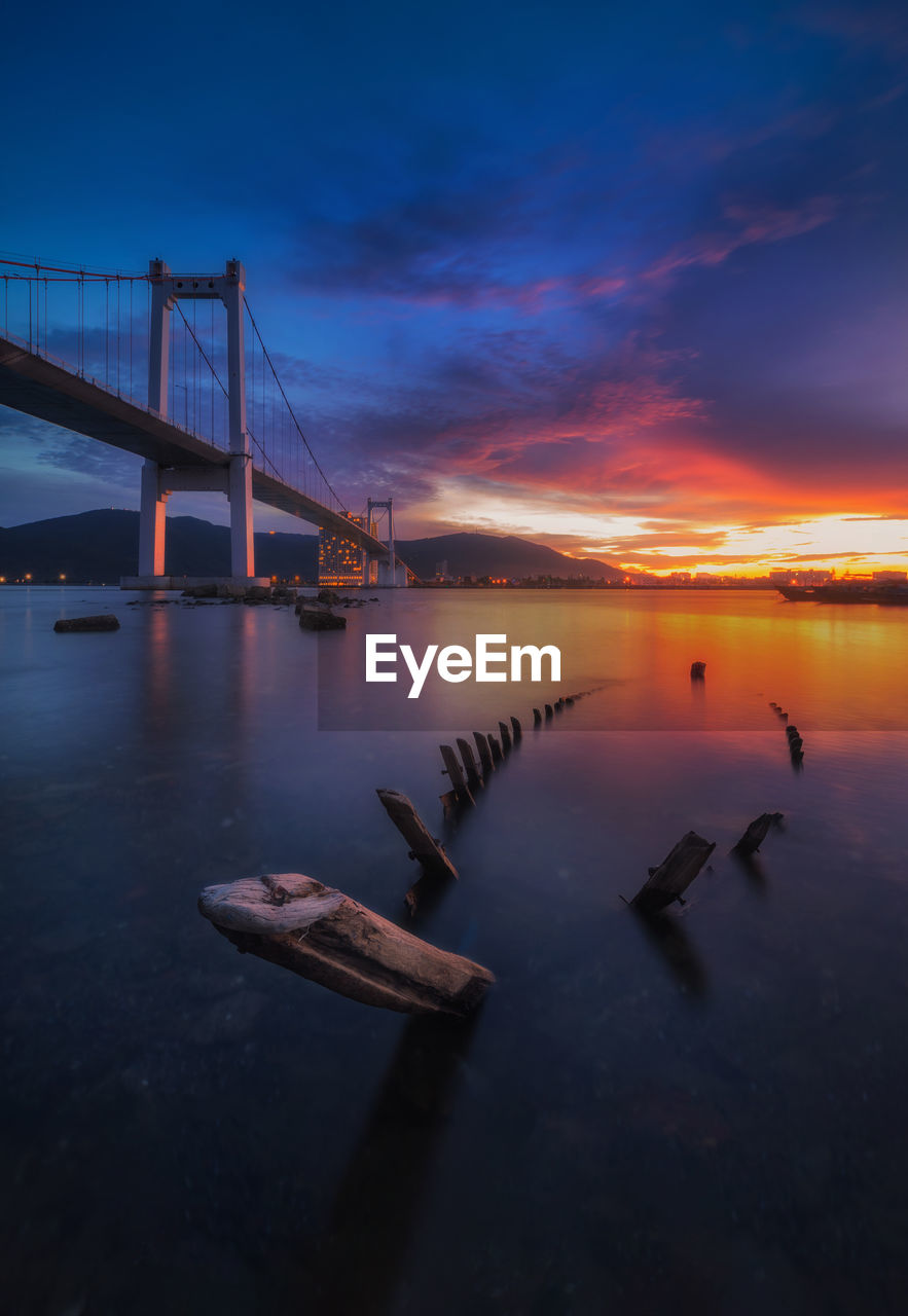 Bridge over sea against sky during sunset