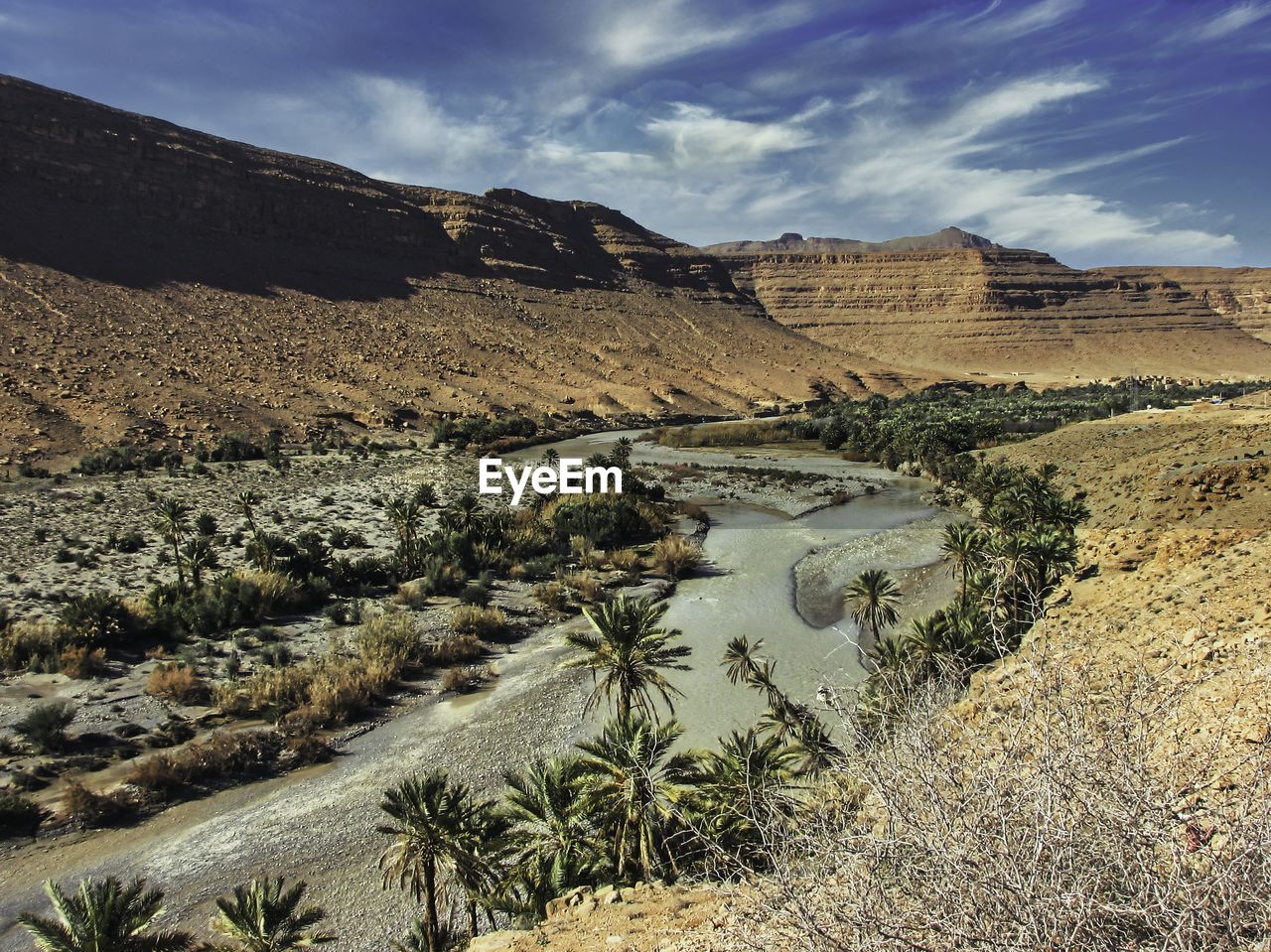 River runing through arid countryside. date palm trees.