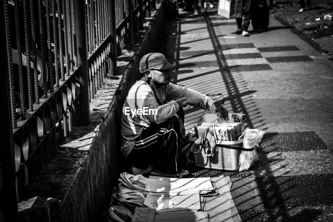 Side view of man selling books and bags on footpath