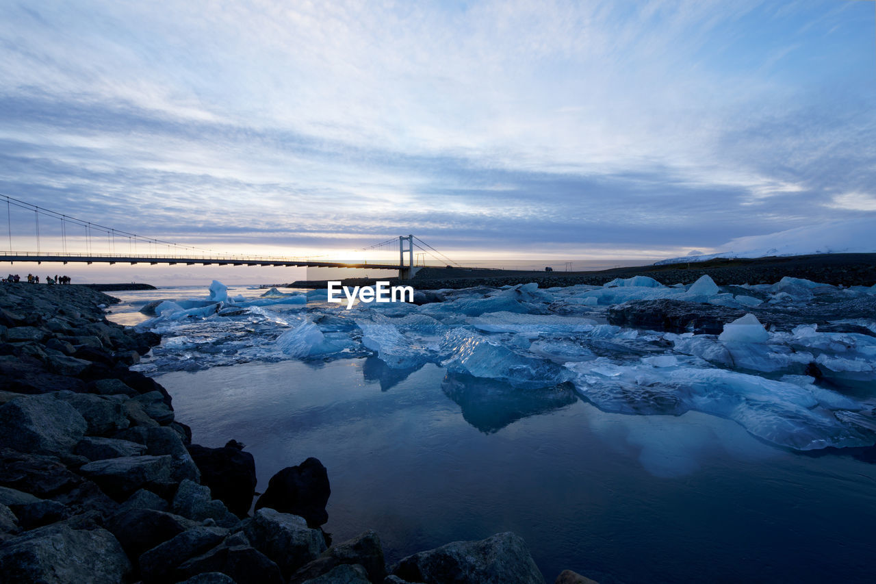 SNOW COVERED ROCKS BY SEA AGAINST SKY