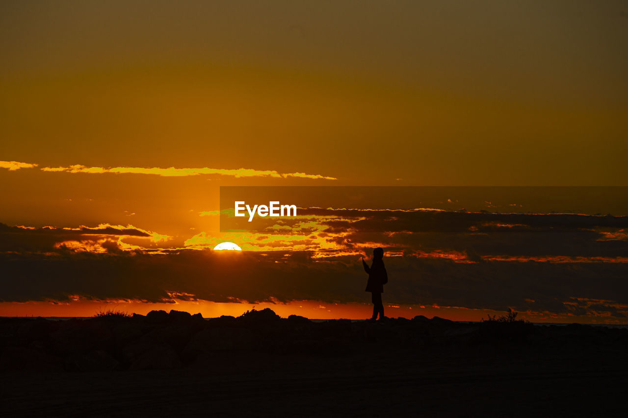 Sunset on the beach. silhouettes of people on the beach breakwater person