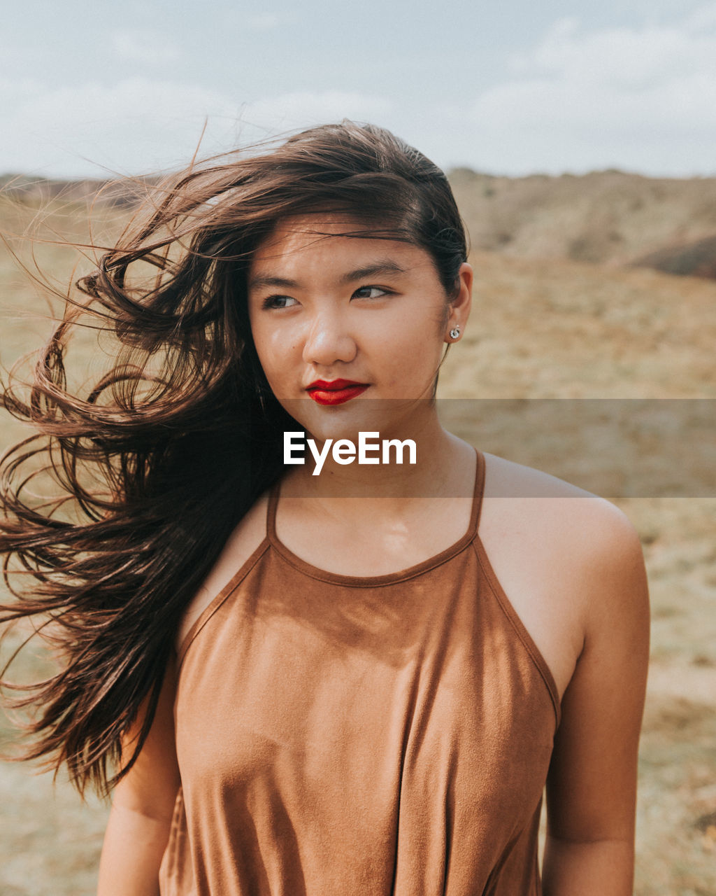 Portrait of beautiful young woman standing against sky