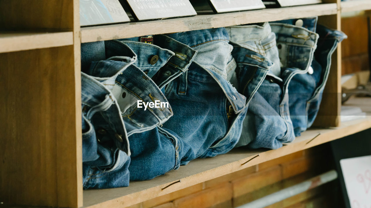 Close-up of jeans in shelf at store for sale