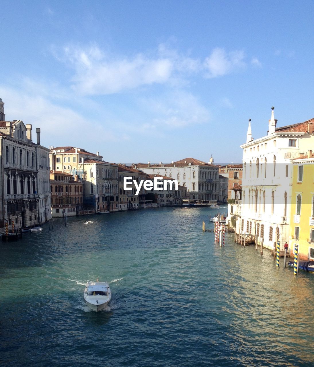 Boats in canal amidst buildings in city against sky