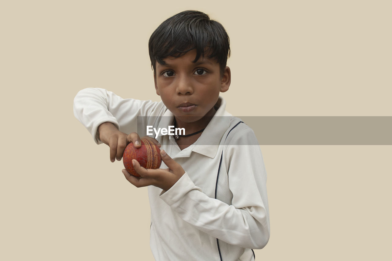 PORTRAIT OF BOY HOLDING CAMERA OVER GRAY BACKGROUND